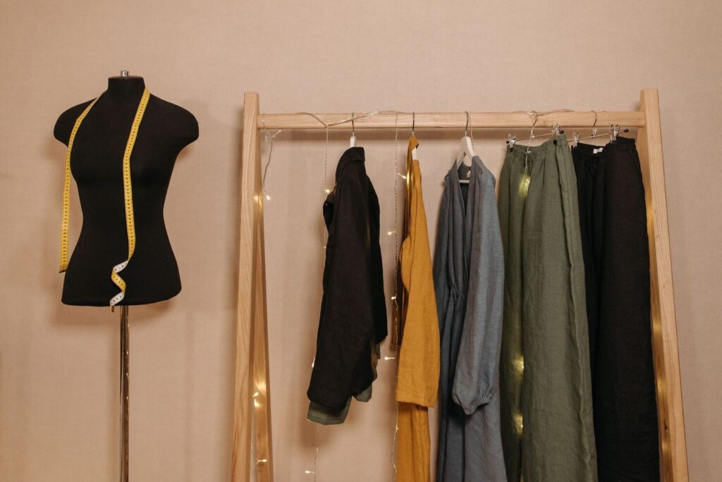 Dress form and neutral clothing arranged on a wooden garment rack