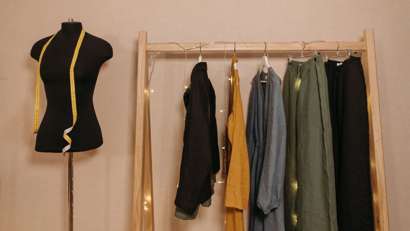 Dress form and neutral clothing arranged on a wooden garment rack
