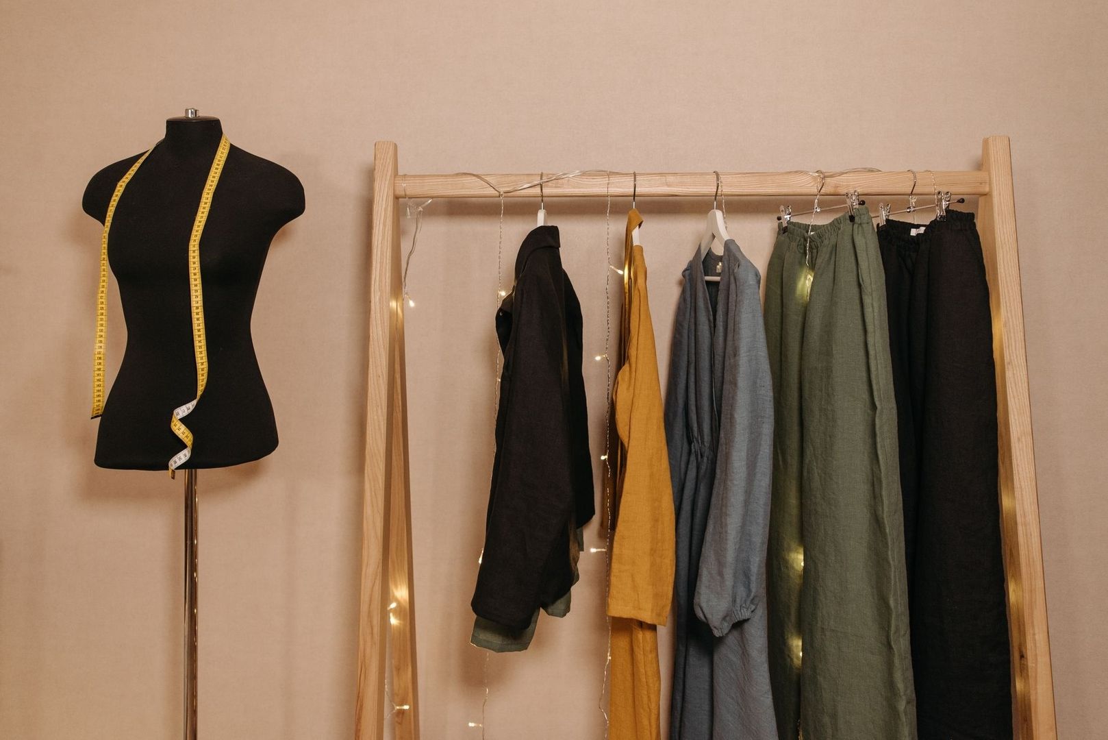 Dress form and neutral clothing arranged on a wooden garment rack