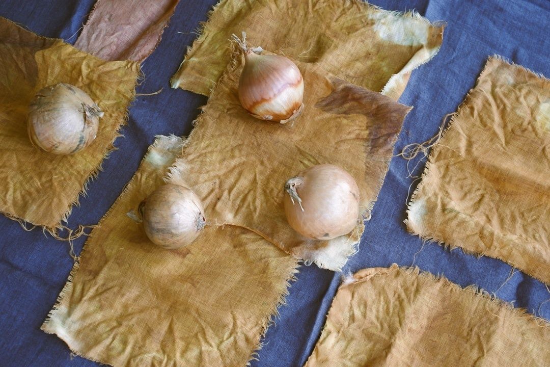 Onions resting on naturally dyed, frayed linen swatches