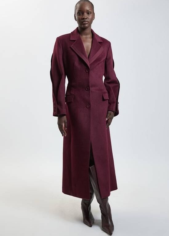 Model wearing a burgundy tailored wool coat with knee-high boots