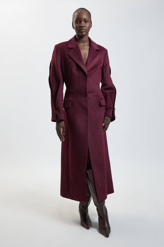 Model wearing a burgundy tailored wool coat with knee-high boots